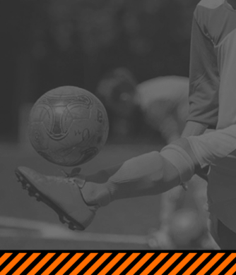 Un joueur de football en action, en train de frapper un ballon avec sa jambe, sur un terrain en noir et blanc, avec un motif orange et noir en bas à droite.